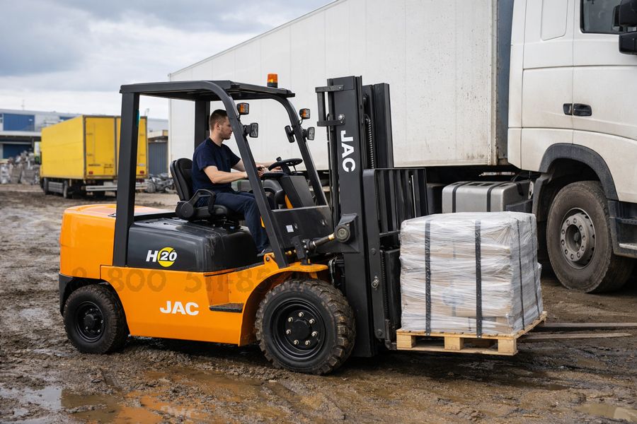 дизельный погрузчик выполняет погрузку рядом с грузовым автомобилем на грязном покрытии