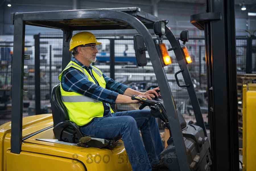 Оператор вилочного погрузчика в кабине с эргономичным сиденьем и хорошей обзорностью, работа на складе среди стеллажей и паллет.