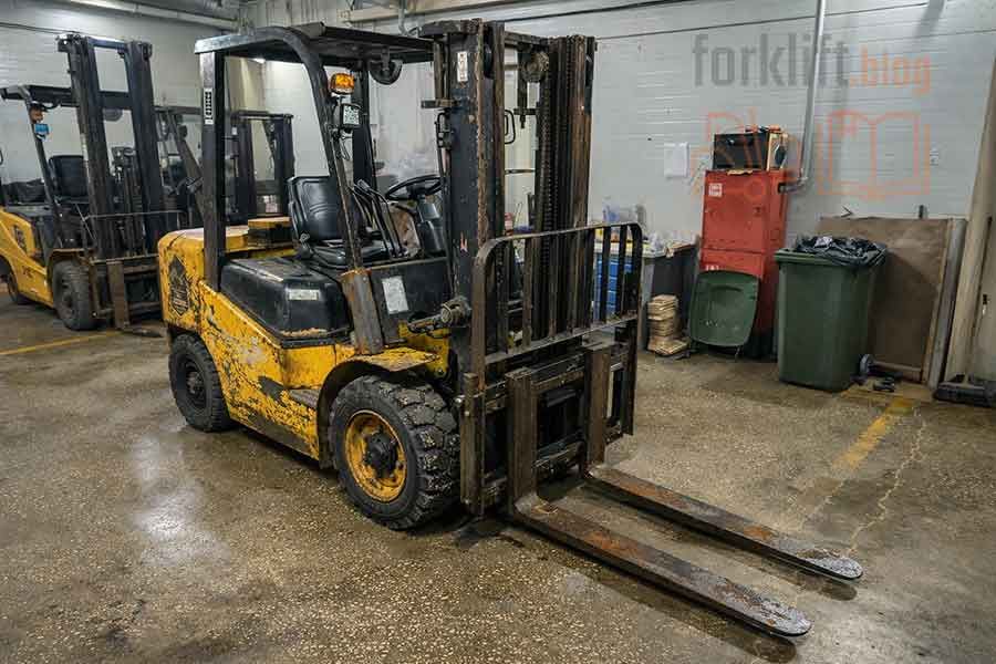 Сильно изношенный вилочный погрузчик с коррозией и повреждениями в ремонтной зоне, техника, требующая списания и утилизации для обновления складского парка.